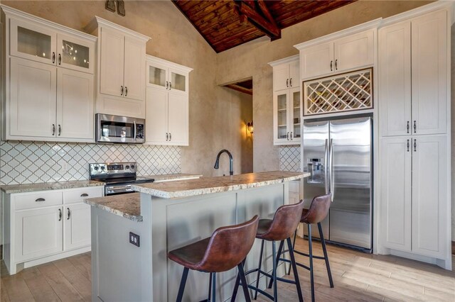 kitchen featuring white cabinets, stainless steel appliances, wood ceiling, and an island with sink