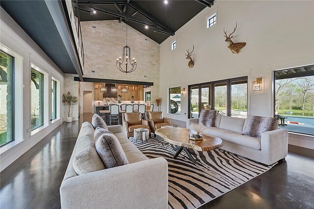 living room featuring a wealth of natural light, french doors, high vaulted ceiling, and a chandelier