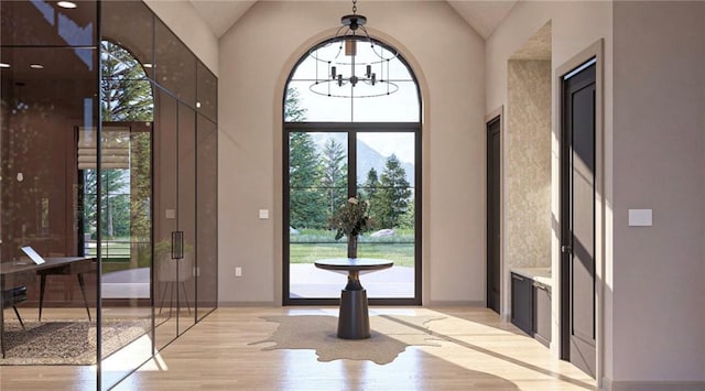 doorway featuring high vaulted ceiling, a wealth of natural light, a chandelier, and light hardwood / wood-style flooring