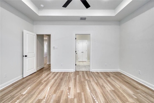 unfurnished bedroom featuring a tray ceiling and light hardwood / wood-style floors