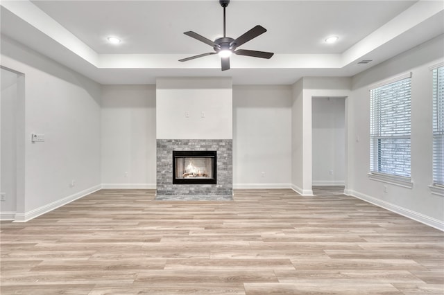 unfurnished living room featuring ceiling fan, a multi sided fireplace, and light wood-type flooring