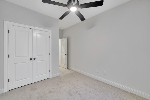 unfurnished bedroom with ceiling fan, light carpet, and a closet