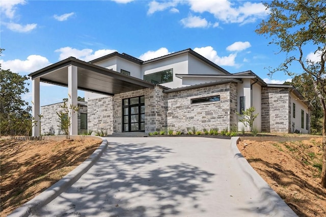 view of front of property with stucco siding, stone siding, and driveway