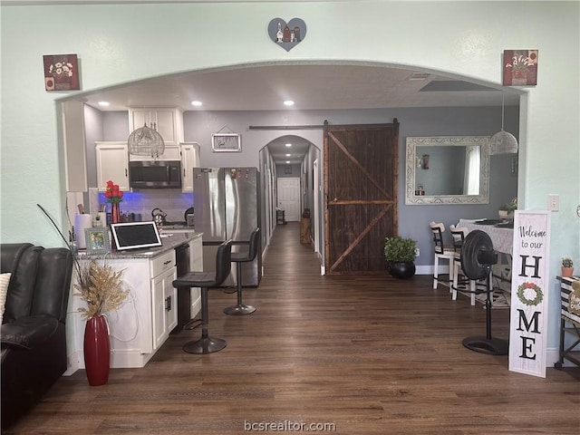 kitchen with appliances with stainless steel finishes, a barn door, white cabinetry, and dark wood-type flooring