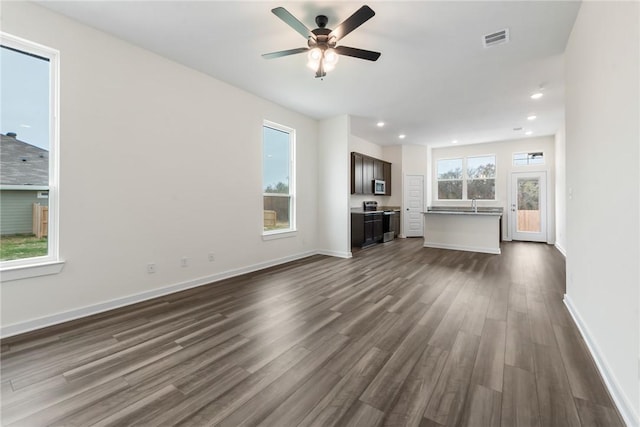 unfurnished living room with ceiling fan, plenty of natural light, and dark hardwood / wood-style flooring