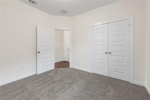 unfurnished bedroom with a closet and dark colored carpet