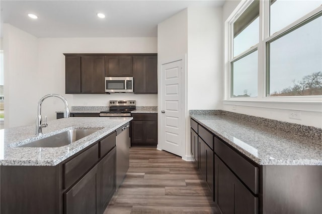 kitchen with light stone counters, stainless steel appliances, sink, and dark brown cabinets