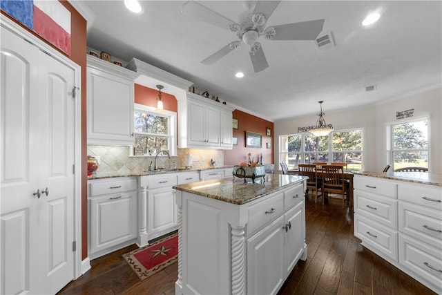 kitchen featuring white cabinetry, a kitchen island, decorative light fixtures, and dark hardwood / wood-style floors