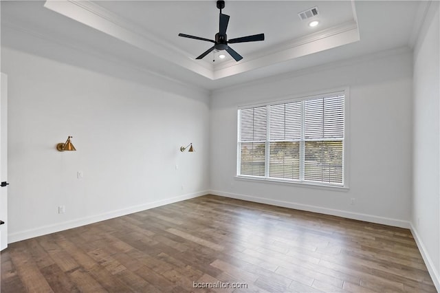 empty room featuring a tray ceiling, crown molding, ceiling fan, and hardwood / wood-style flooring