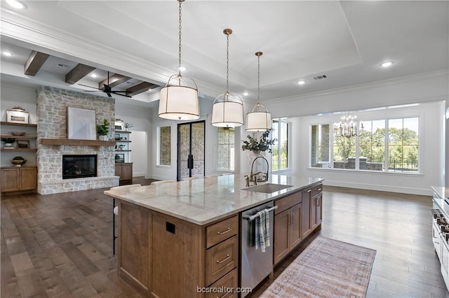 kitchen with light stone countertops, sink, dark wood-type flooring, an island with sink, and pendant lighting