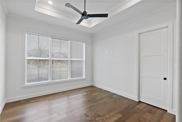 spare room with dark hardwood / wood-style flooring, a tray ceiling, ceiling fan, and crown molding