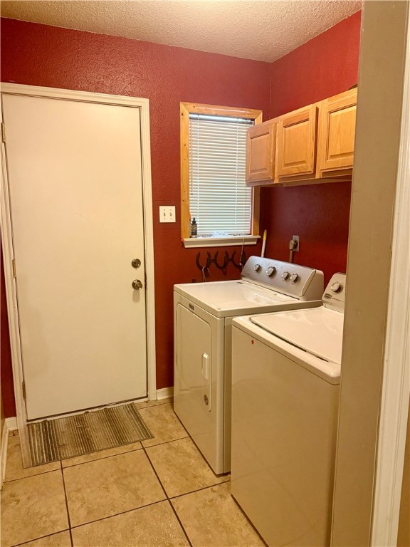 7704 Deer Trail Dr, Bryan, TX 77807 - washroom featuring washing machine and dryer, cabinet space, light tile patterned flooring, and a textured ceiling