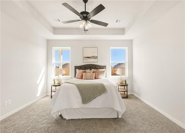 carpeted bedroom featuring a tray ceiling and ceiling fan