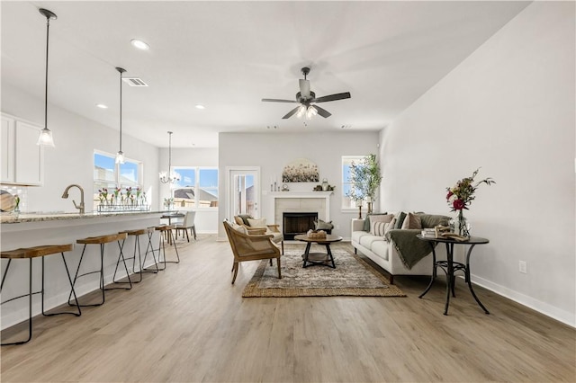 living room with light hardwood / wood-style flooring and ceiling fan with notable chandelier