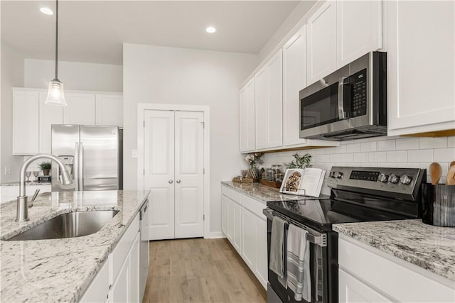 kitchen with white cabinets, sink, appliances with stainless steel finishes, and light hardwood / wood-style flooring