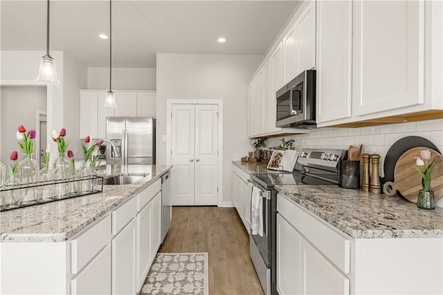 kitchen featuring sink, decorative light fixtures, light hardwood / wood-style floors, white cabinetry, and stainless steel appliances