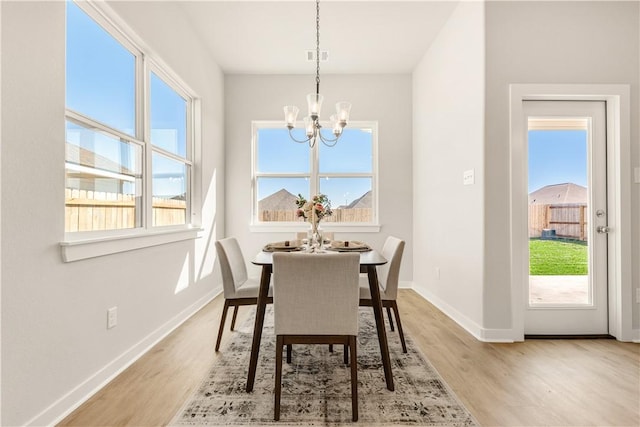 dining space with light hardwood / wood-style flooring and a notable chandelier