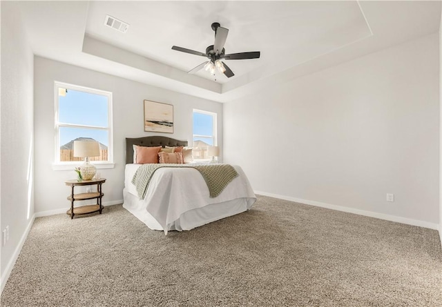 bedroom featuring a raised ceiling, ceiling fan, and carpet flooring