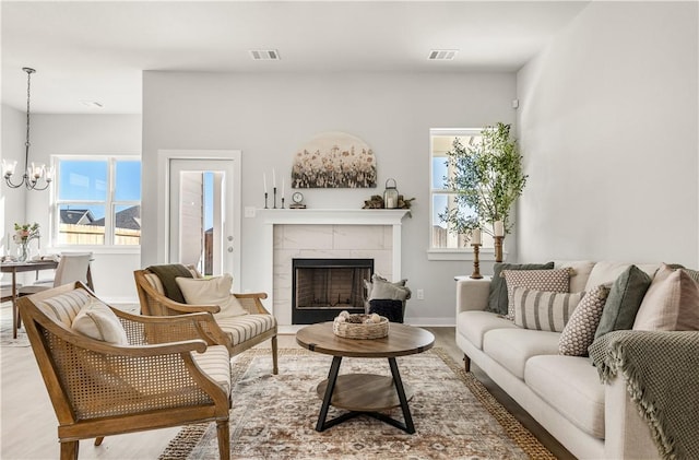 living room featuring a fireplace, an inviting chandelier, and light hardwood / wood-style flooring