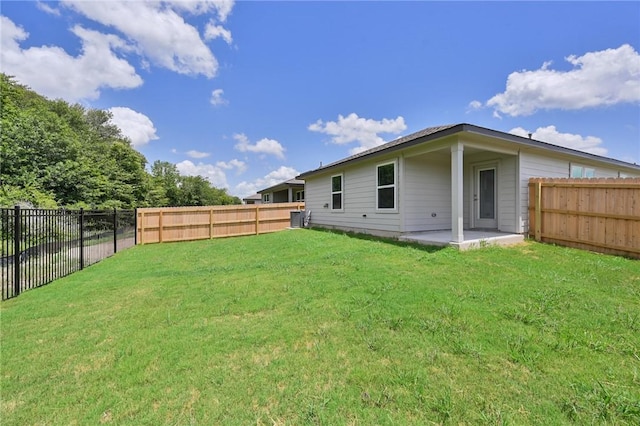 rear view of property with a yard, a patio, and a fenced backyard