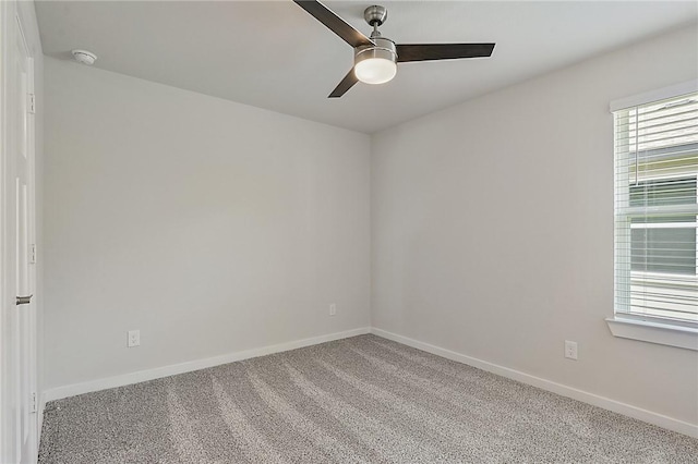 carpeted spare room with a ceiling fan and baseboards