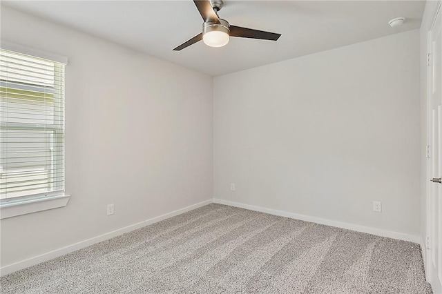 empty room with carpet flooring, a ceiling fan, and baseboards
