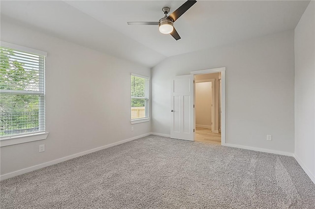 spare room featuring ceiling fan, light carpet, lofted ceiling, and baseboards