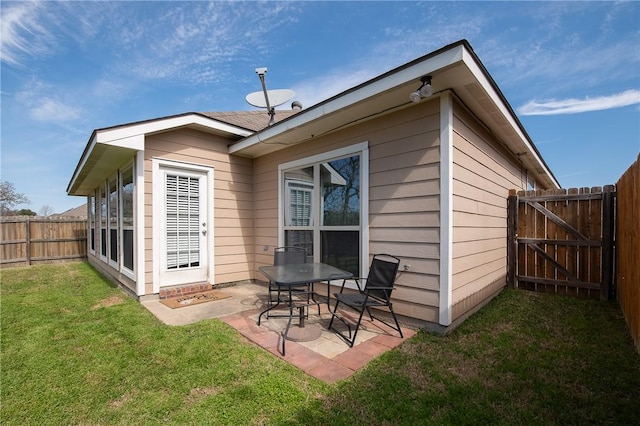 back of property with a gate, a yard, a fenced backyard, and a patio area