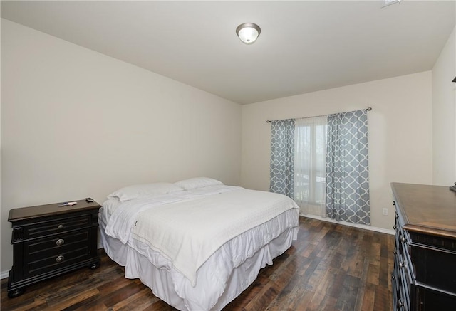 bedroom with dark wood finished floors and baseboards