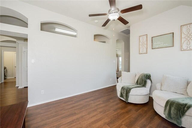 sitting room featuring visible vents, baseboards, wood finished floors, arched walkways, and a ceiling fan