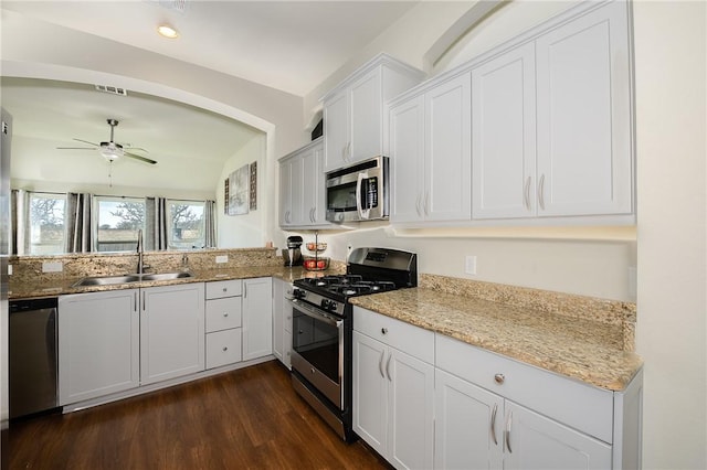 kitchen featuring dark wood finished floors, light stone countertops, appliances with stainless steel finishes, and a sink