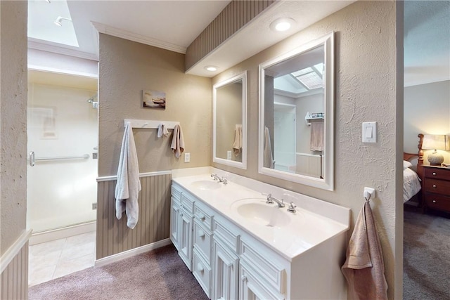 bathroom with double vanity, a textured wall, a sink, and ensuite bathroom