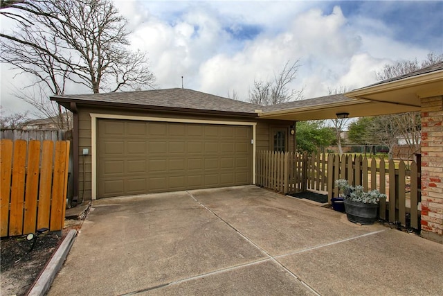 garage with fence and concrete driveway