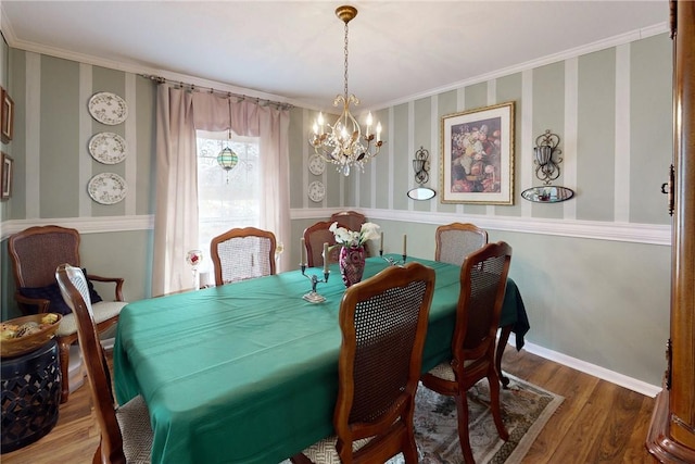 dining area featuring a chandelier, ornamental molding, wood finished floors, and baseboards