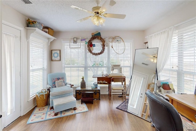 sitting room featuring a textured ceiling, wood finished floors, and a healthy amount of sunlight