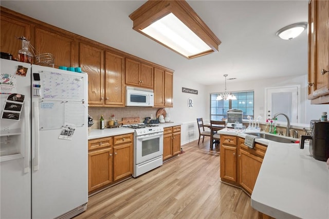 kitchen featuring white appliances, a sink, decorative backsplash, light wood finished floors, and light countertops