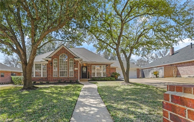 view of front of property with a garage, brick siding, driveway, and a front lawn