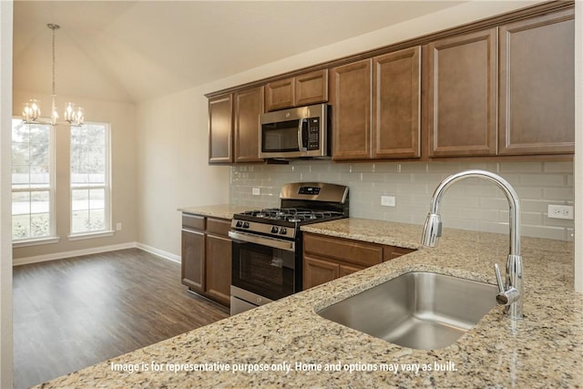 kitchen with dark wood-type flooring, sink, vaulted ceiling, light stone counters, and stainless steel appliances