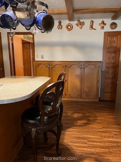 kitchen featuring beam ceiling and dark wood-type flooring