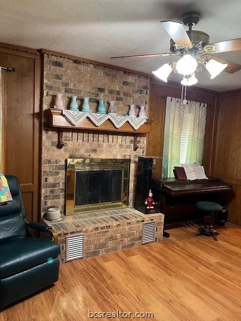 489 County Road 265, Snook, TX 77878 - living room with a fireplace, a ceiling fan, wood finished floors, and a textured ceiling