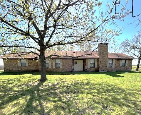 ranch-style home featuring a front lawn and a chimney
