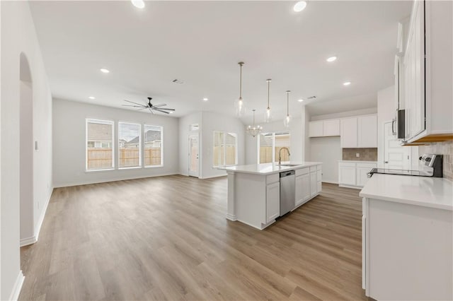 kitchen with sink, white cabinets, hanging light fixtures, stainless steel appliances, and a center island with sink