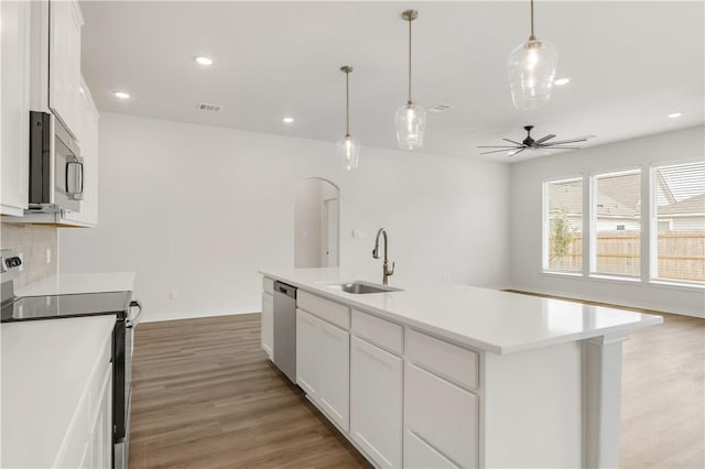 kitchen featuring sink, a kitchen island with sink, stainless steel appliances, white cabinets, and decorative light fixtures