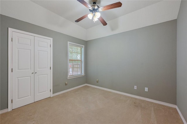 unfurnished bedroom featuring light colored carpet, a closet, and ceiling fan