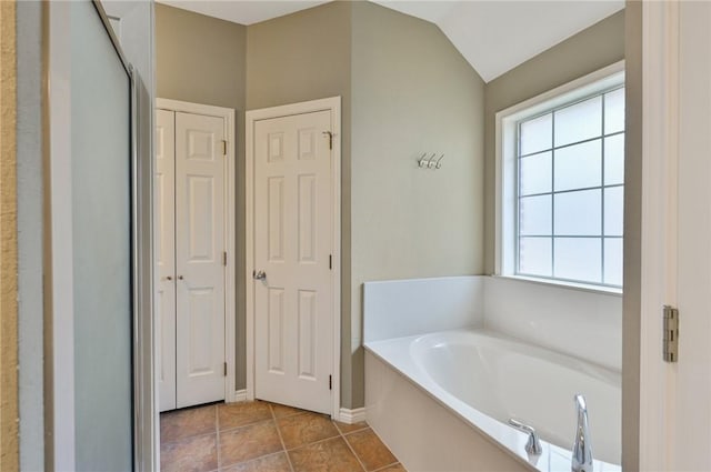 bathroom featuring tile patterned floors, a bath, and vaulted ceiling