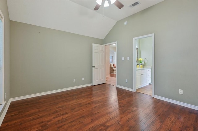 unfurnished bedroom with lofted ceiling, connected bathroom, dark wood-type flooring, and ceiling fan