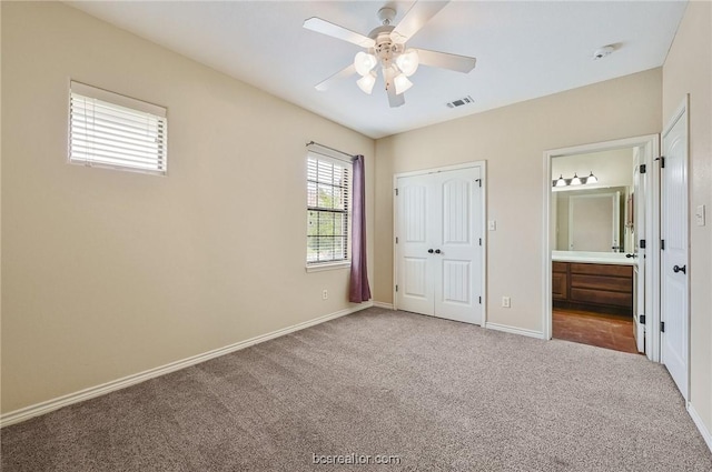 unfurnished bedroom with a closet, carpet floors, ensuite bathroom, and ceiling fan