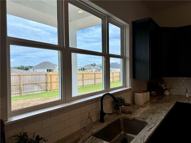 kitchen featuring tasteful backsplash, a wealth of natural light, sink, and light stone counters