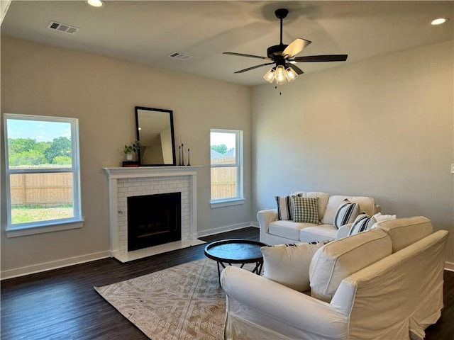 living room featuring ceiling fan, dark hardwood / wood-style floors, and a brick fireplace