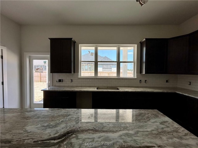 kitchen featuring light stone countertops, decorative backsplash, and a healthy amount of sunlight